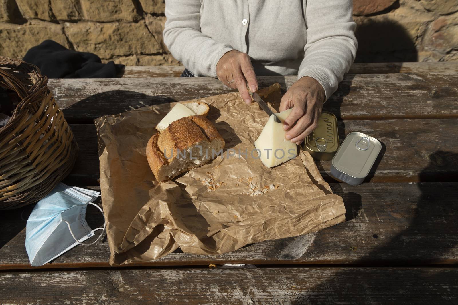 A senior woman, cuts slices of goat cheese at the mountain hut of the fountain of Artica, in Luesia, Spain.