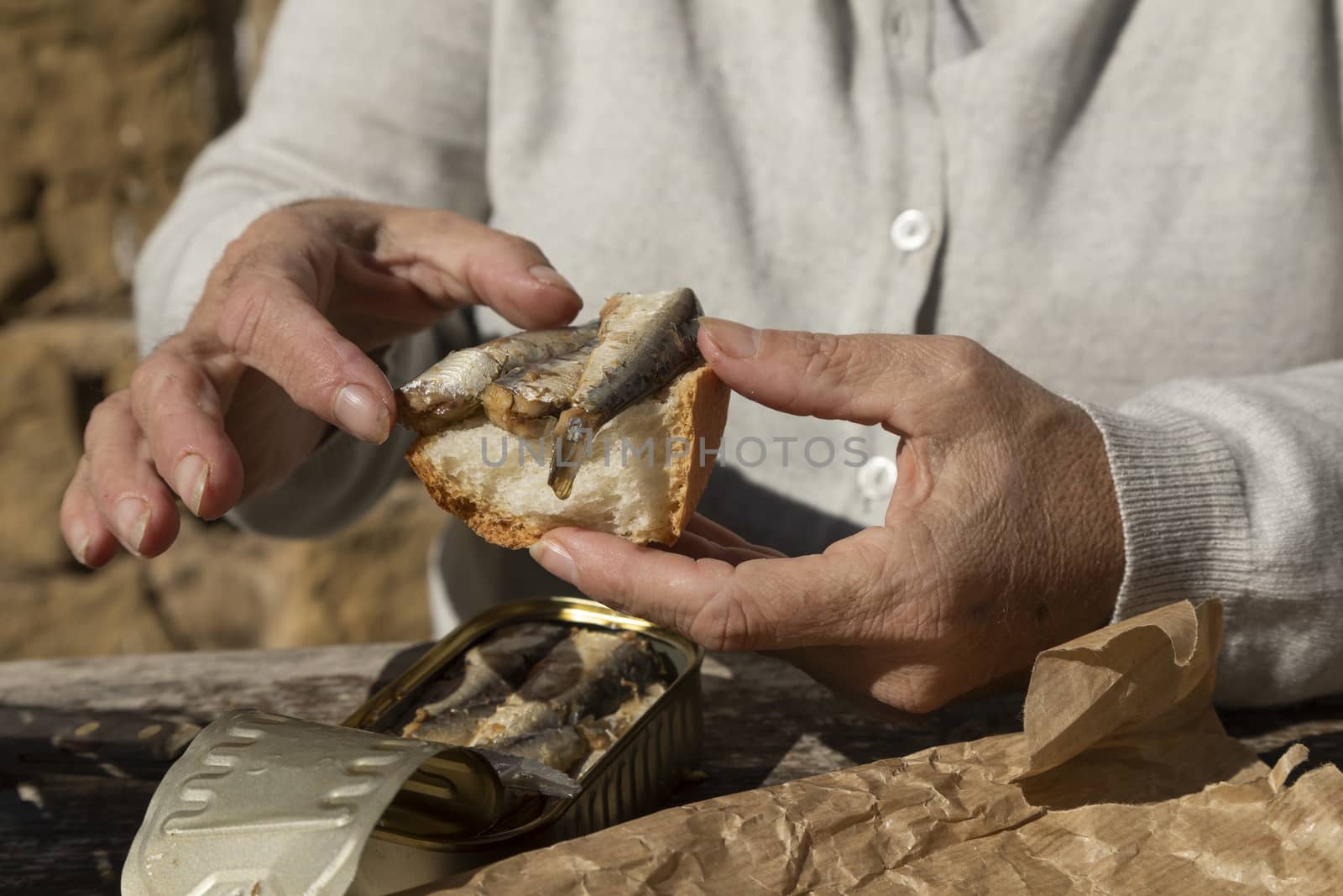 A woman, prepare a slice of bread with canned sardines, Spain by alvarobueno