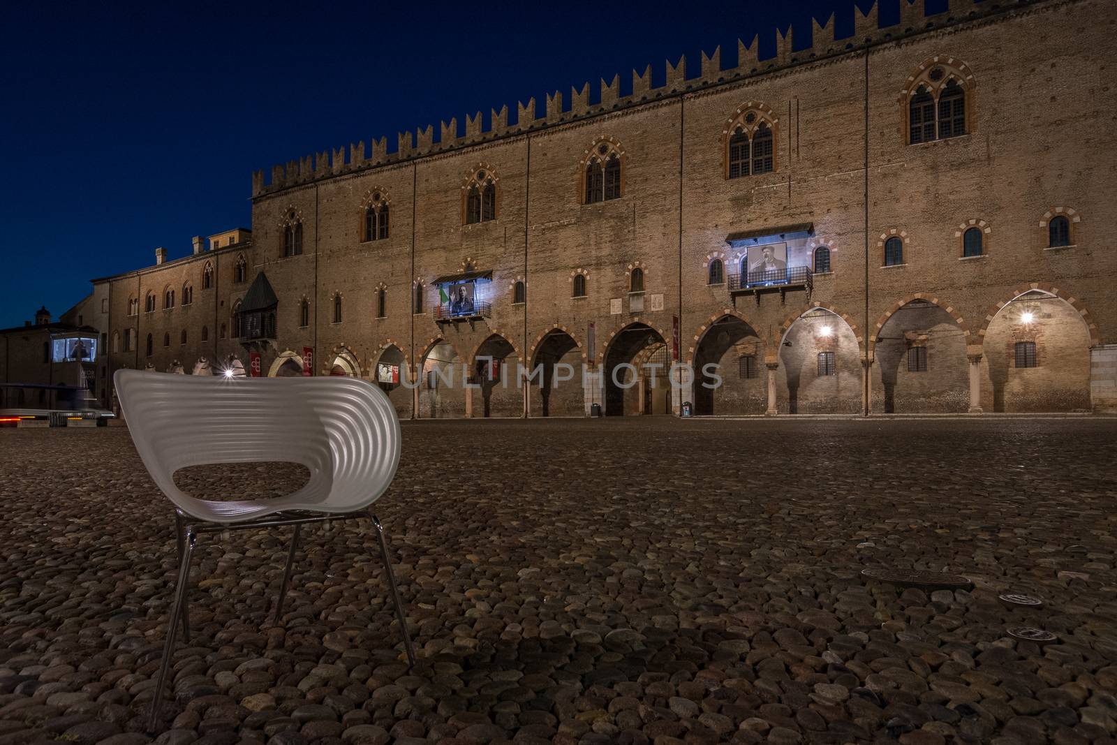 An empty chair in piazza Sordello in the historic Lombard city of Mantua, night photography in Italy