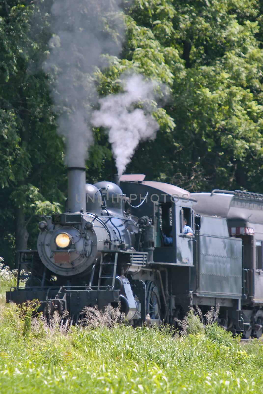 Restored Antique Steam Locomotive with Passenger Cars Steaming Up