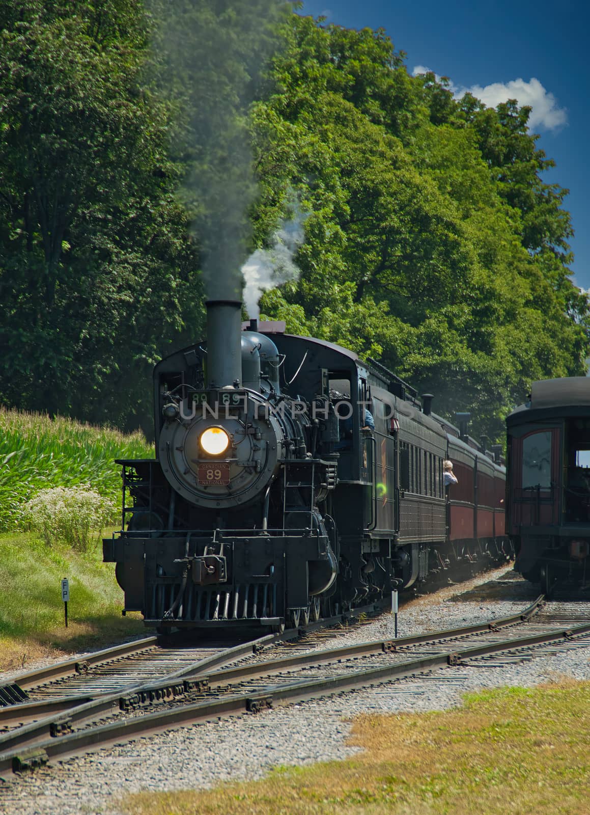 Restored Antique Steam Locomotive with Passenger Cars Steaming Up