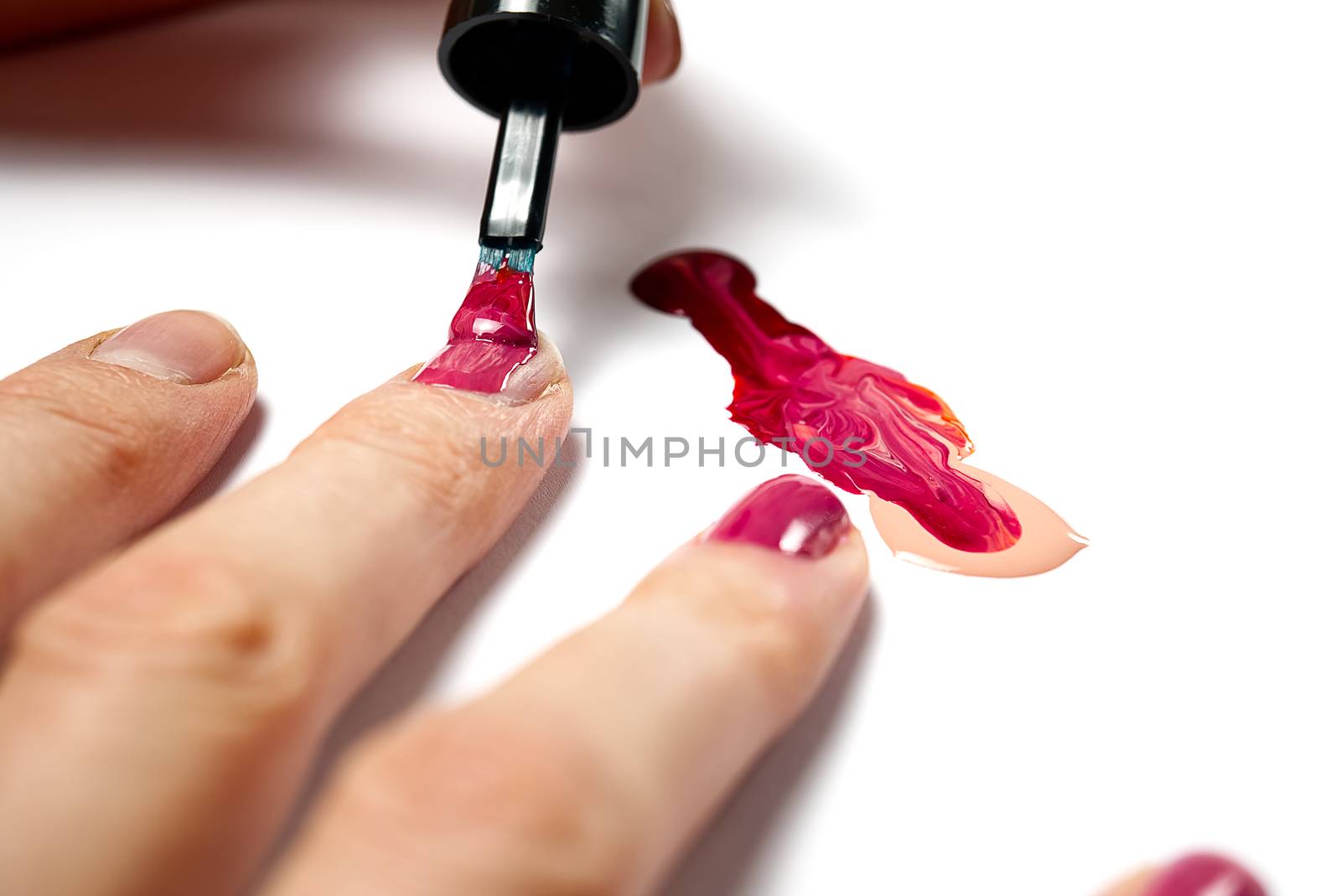 Manicure. Closeup of a woman hand polishing nails manicure. Nail technician manicure at nail salon. Young caucasian woman receiving a french manicure. by PhotoTime