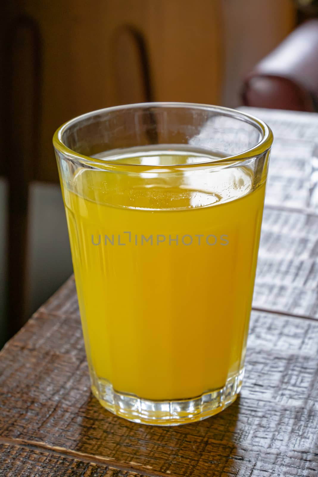 A glass of fresh orange juice drink on brown table in living room.
