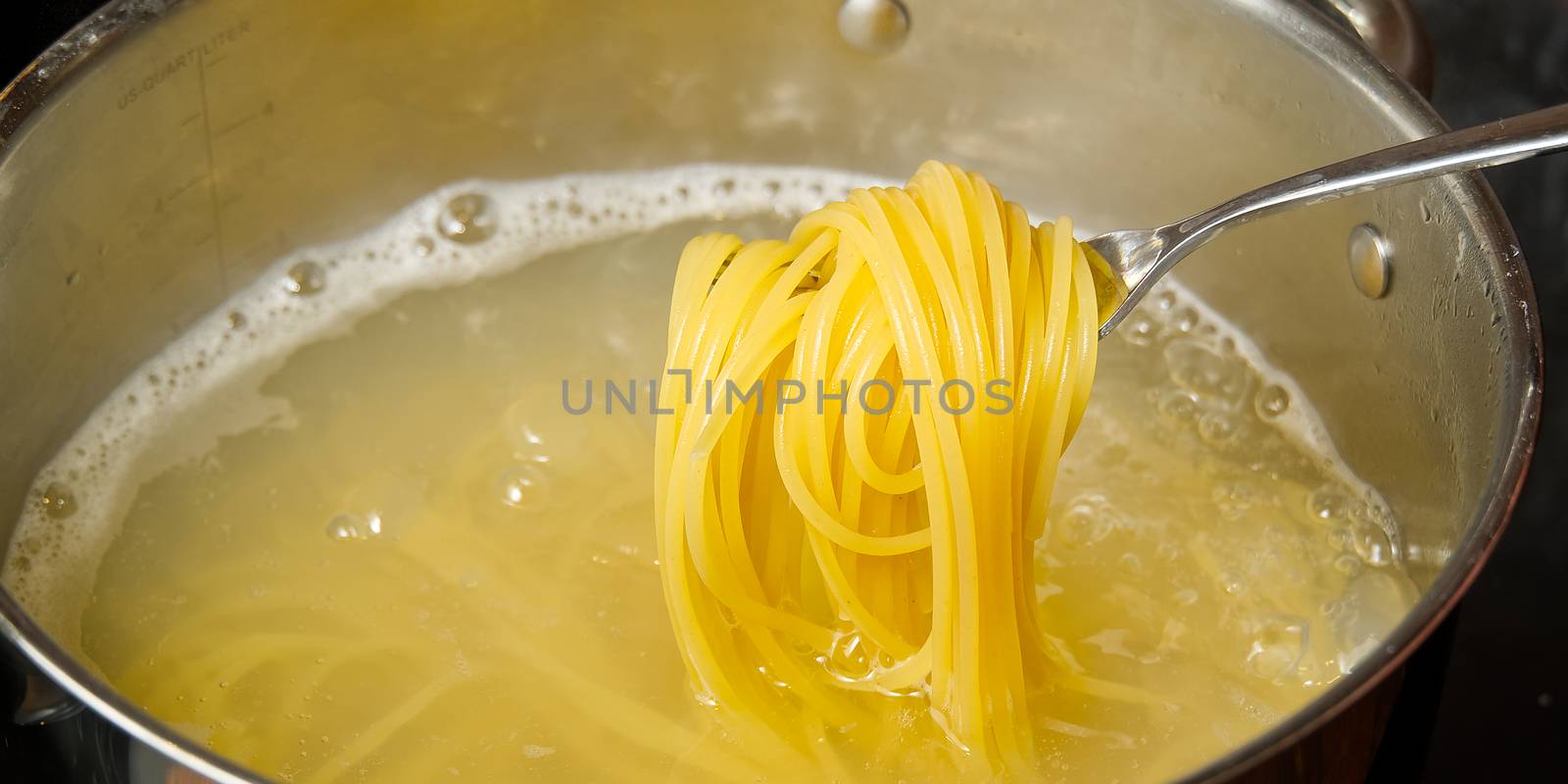Boiling pasta spaghetti in pot. penne rigate pasta- Cooking pasta in boiling water. close up. Checking cooking quality pasta on fork