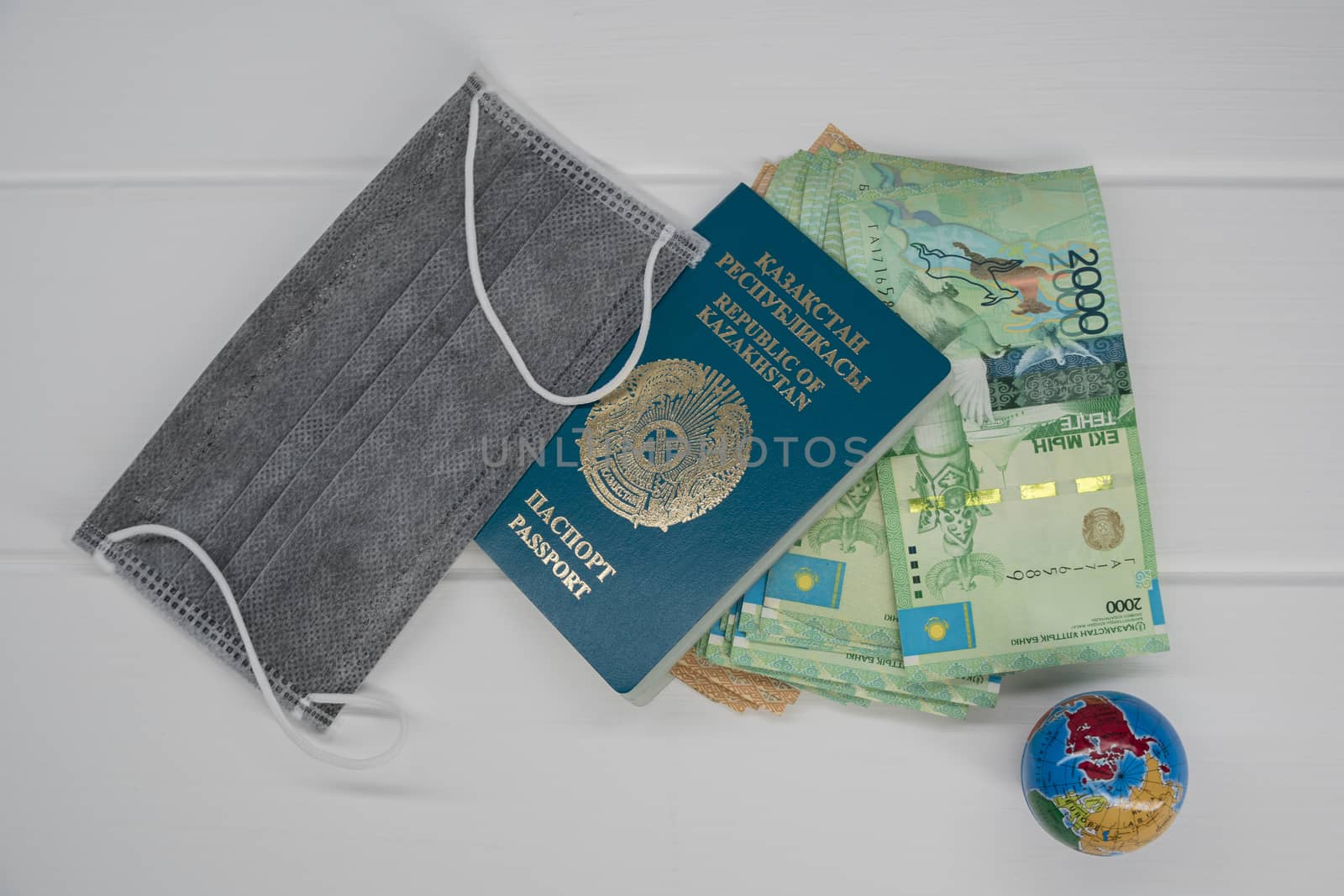 Quarantine in Kazakhstan. Tenge money with medical face masks, a globe, a card and a passport are on the table. The closure of borders and travel in Kazakhstan.