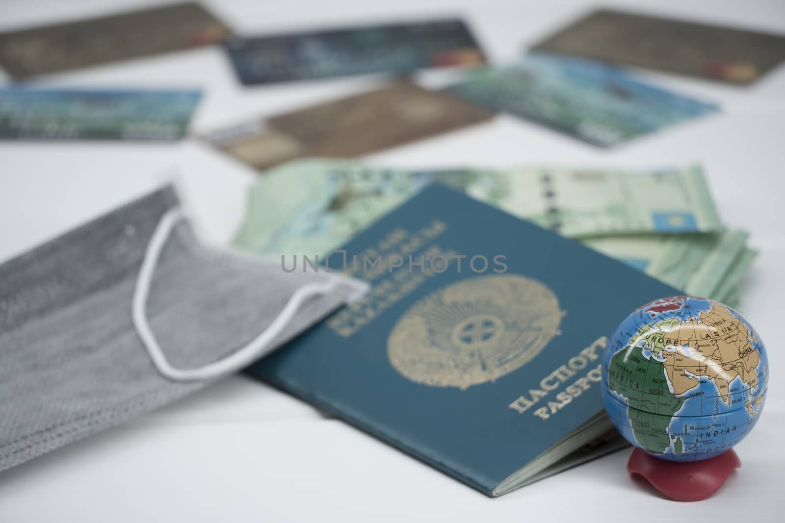 Quarantine in Kazakhstan. Tenge money with medical face masks, a globe, a card and a passport are on the table. The closure of borders and travel in Kazakhstan.