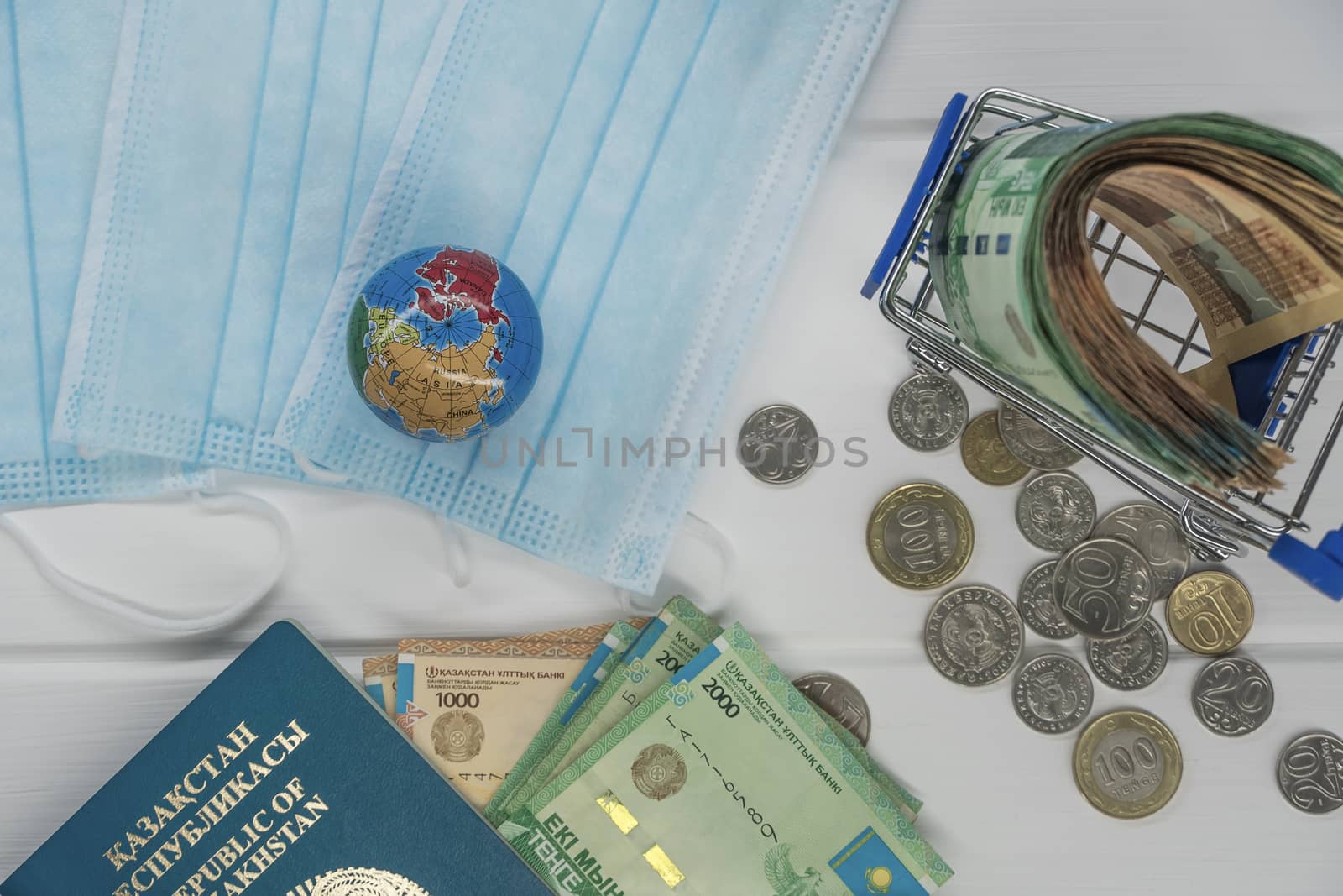 Quarantine in Kazakhstan. Tenge money with medical face masks, a globe, a card and a passport are on the table. The closure of borders and travel in Kazakhstan.