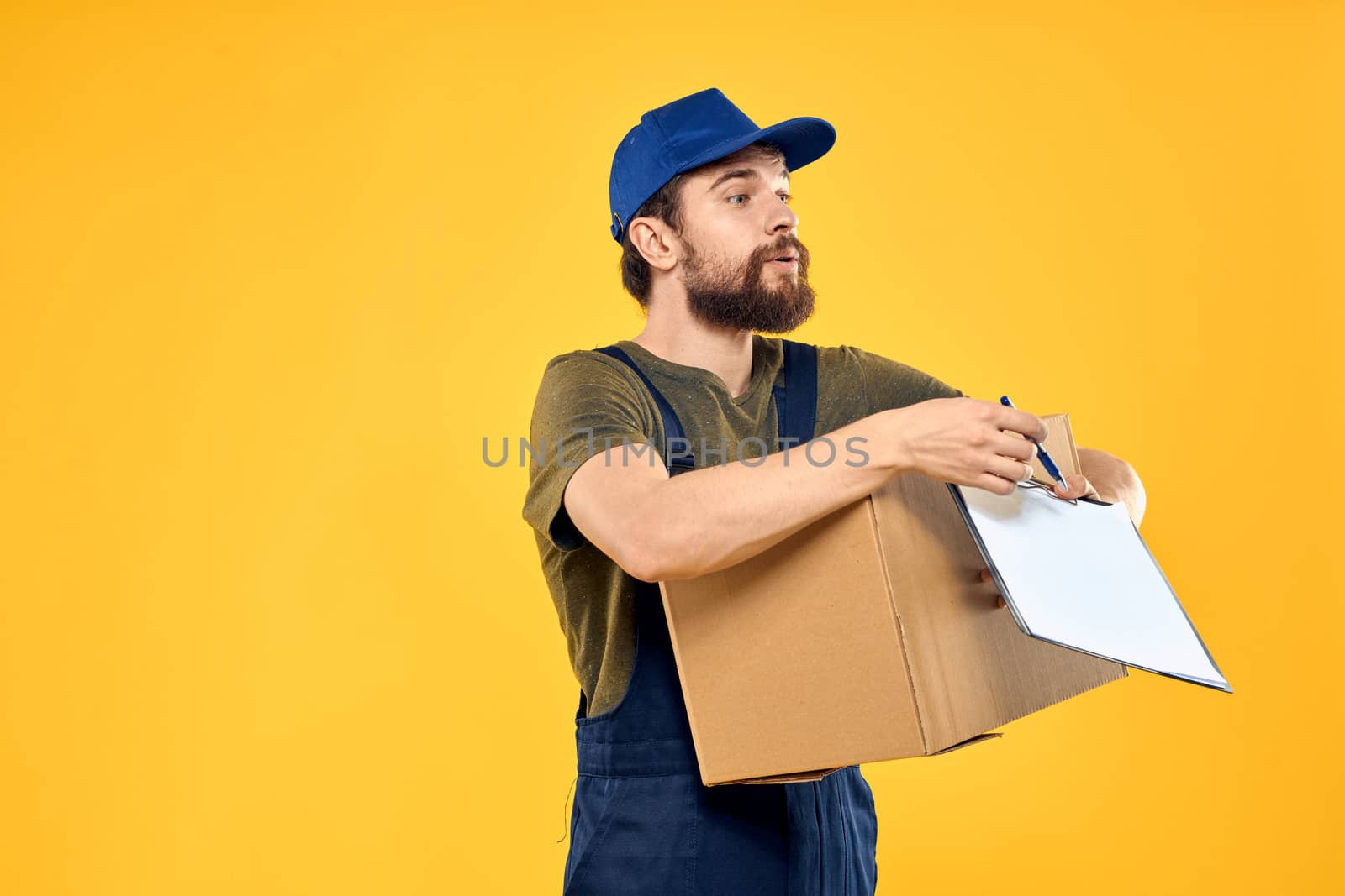 Worker male courier delivering boxes packaging documents yellow background. High quality photo