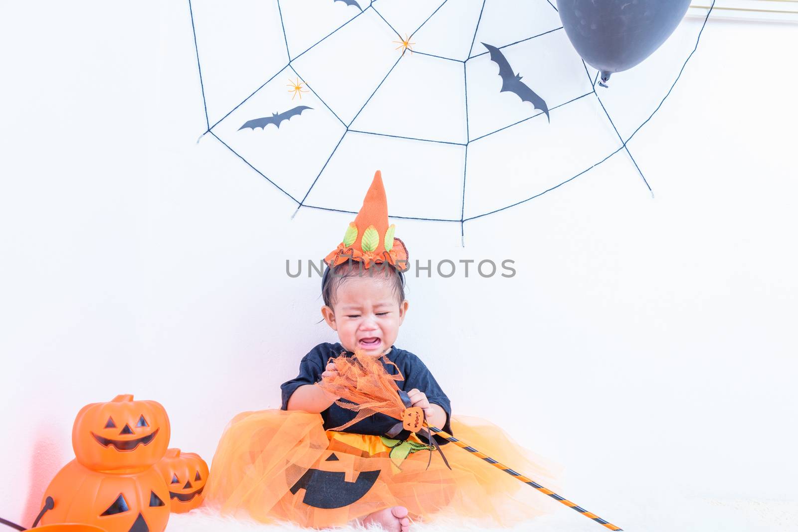 Funny happy baby girl in Halloween costume with pumpkin Jack by Sorapop