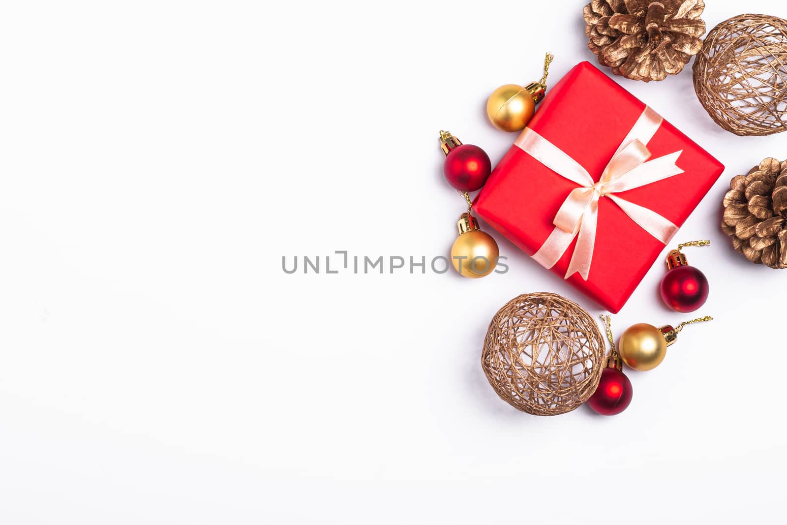 Christmas composition. Red gift box, pine cones, gold and red ornament decorations on white background. Winter holidays concept. Top view copy space