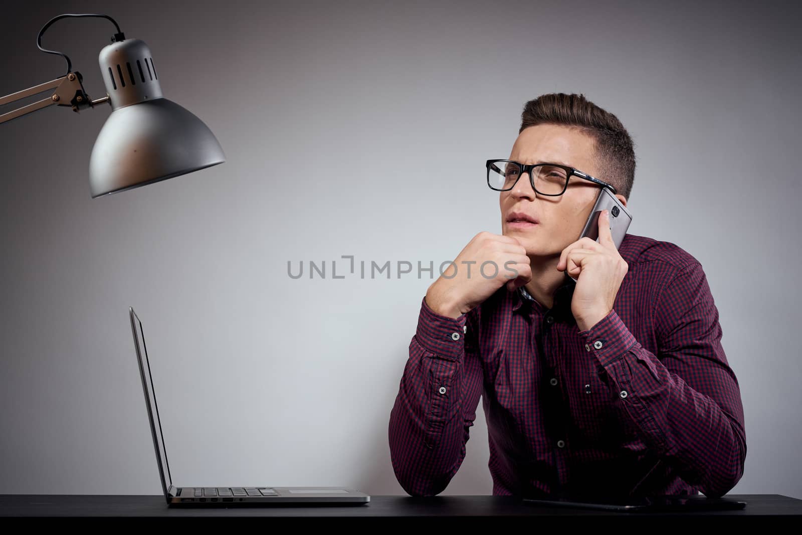 businessman in glasses and a shirt sits at a table with open laptops Coffee Space mobile phone by SHOTPRIME