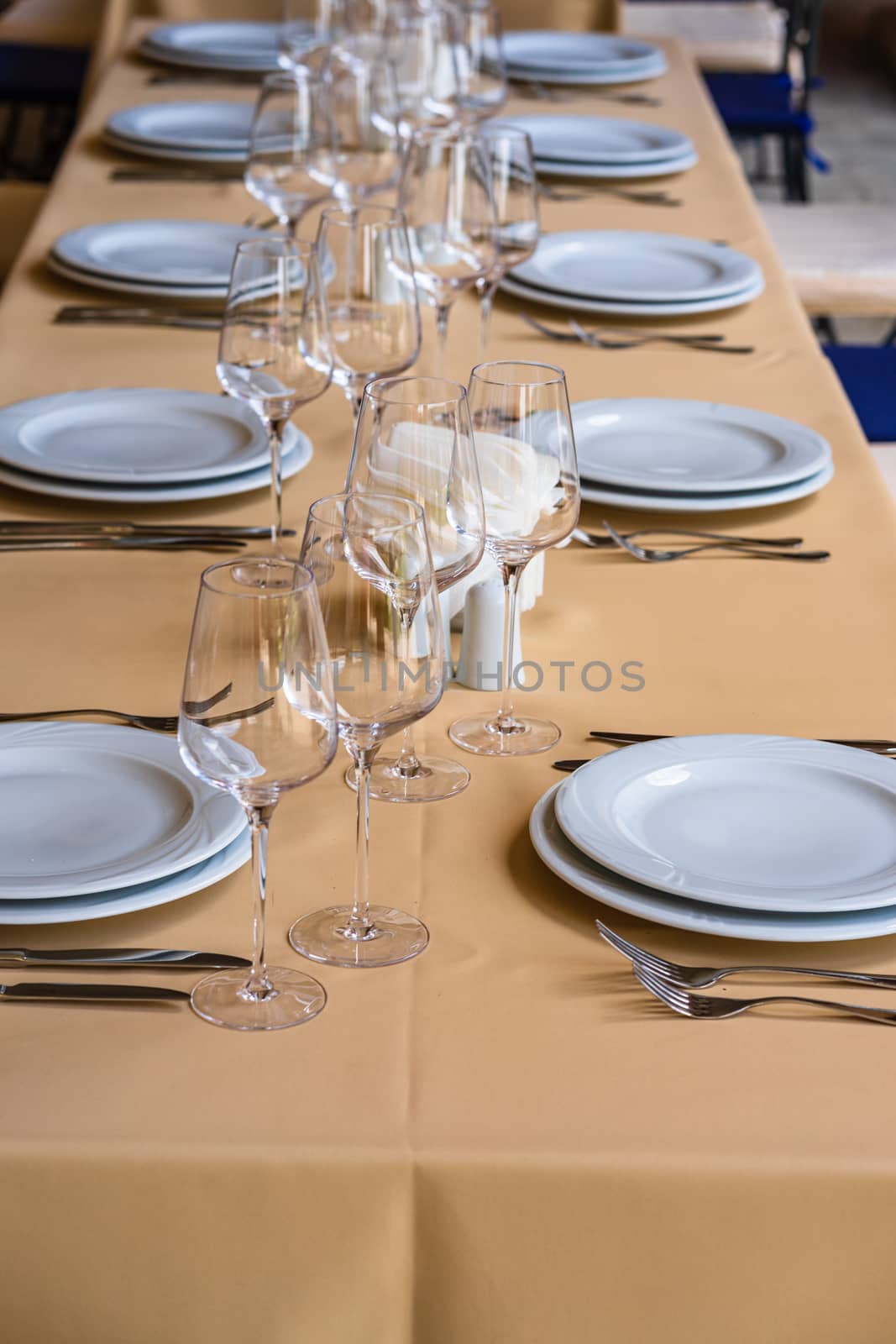 Close up of a festive table setting with empty wine glasses and white plates. Table setting for special events.