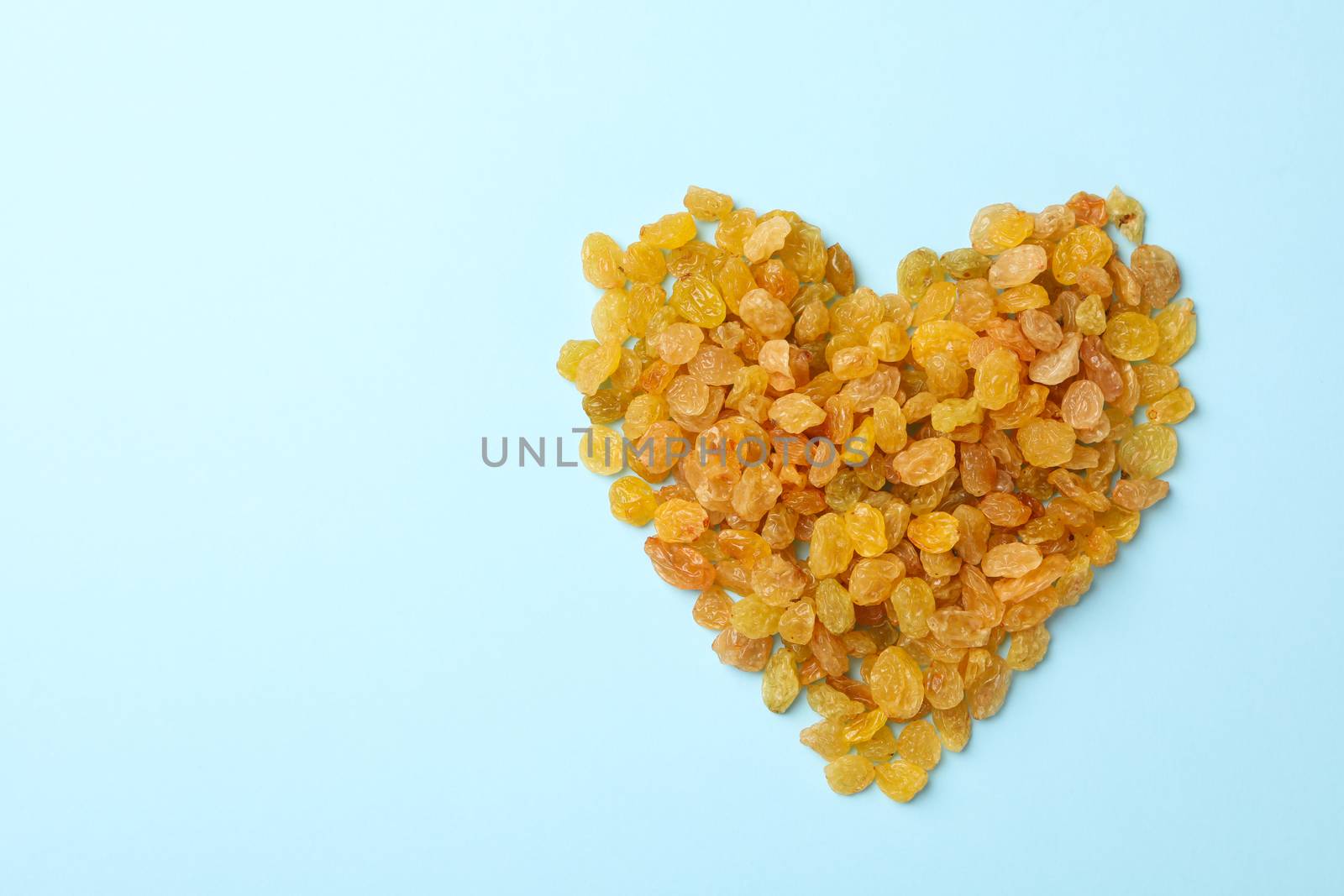 Heart made of raisins on blue background