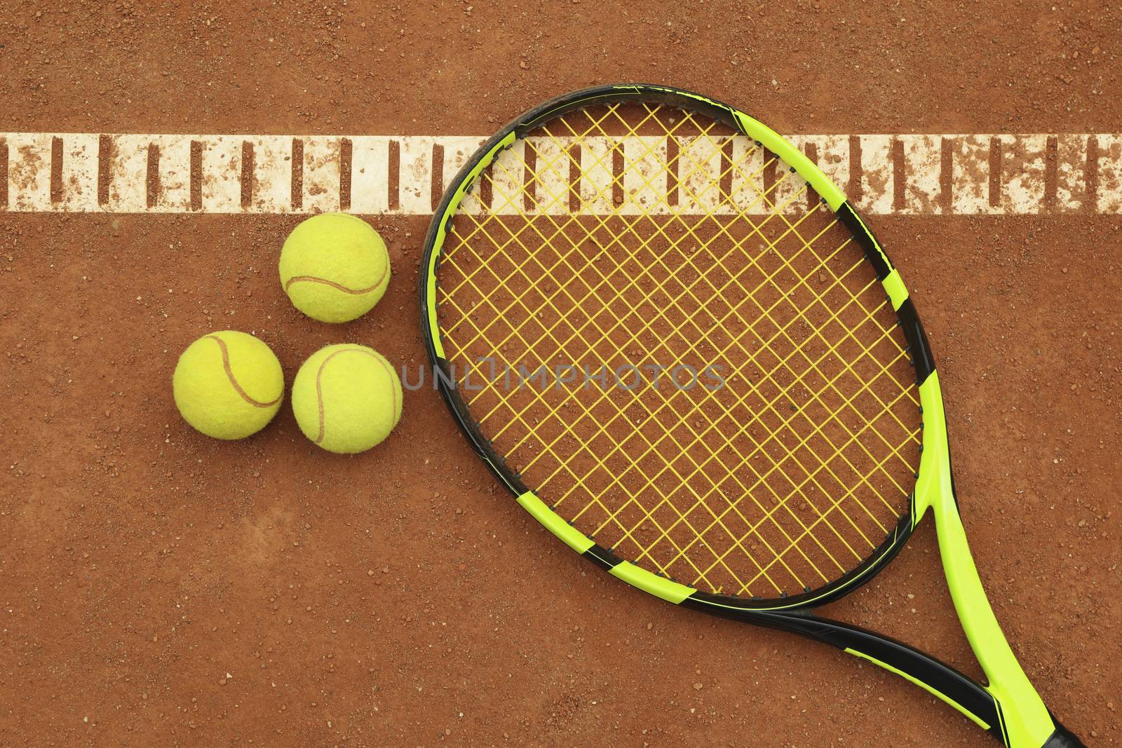 Tennis racquet with tennis balls on clay court