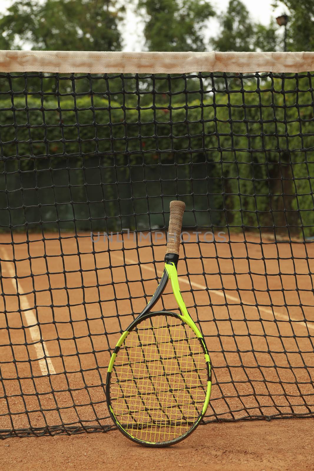 Net with tennis racket on clay court by AtlasCompany