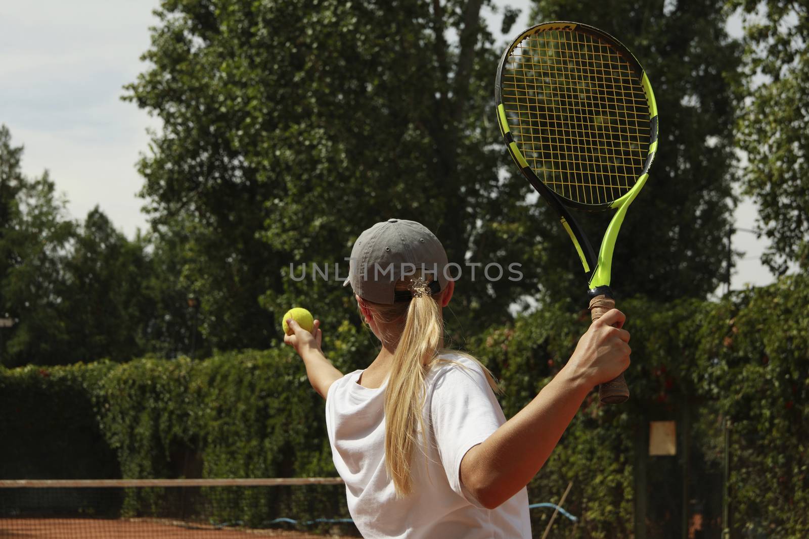 Young woman in white t-shirt serve the tennis ball