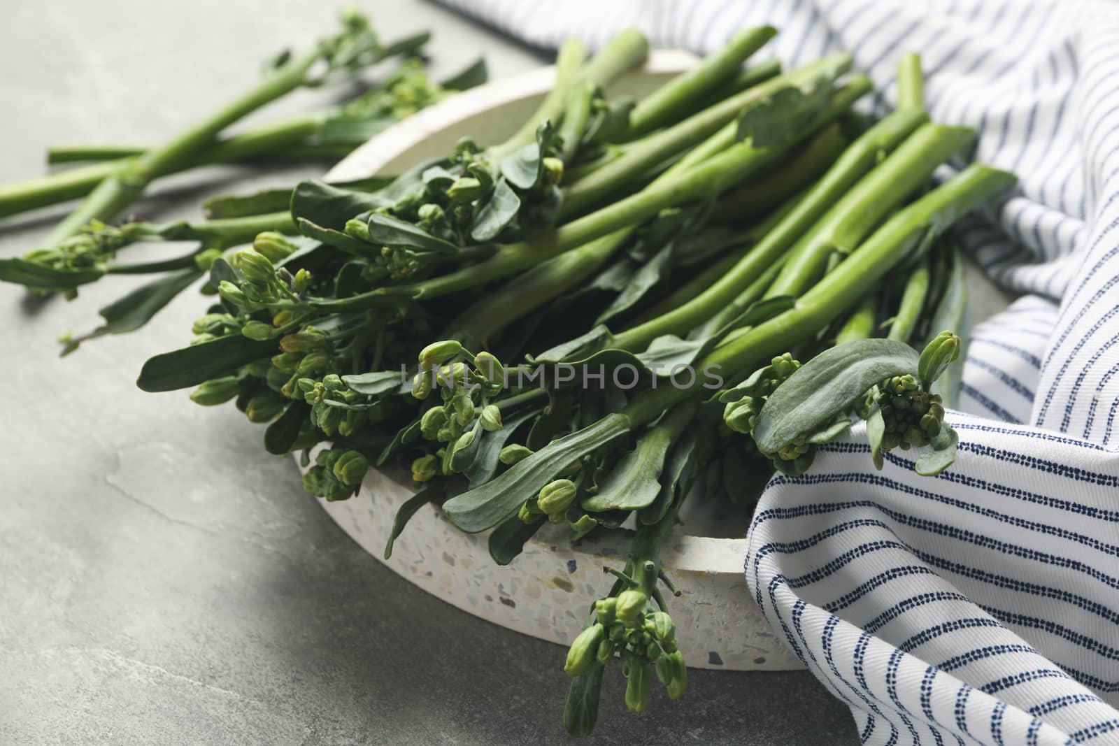 Tray with broccolini and napkin on gray background