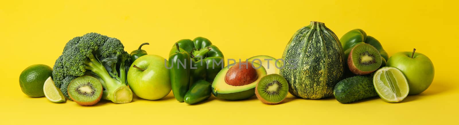 Green vegetables and fruits on yellow background