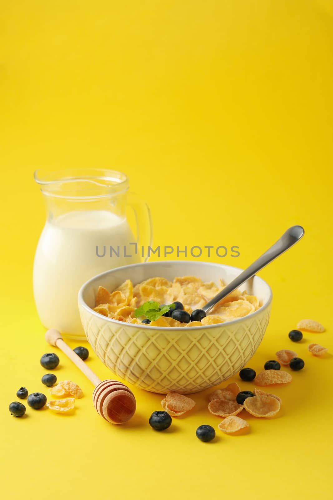 Milk, bowl of muesli and dipper on yellow background by AtlasCompany
