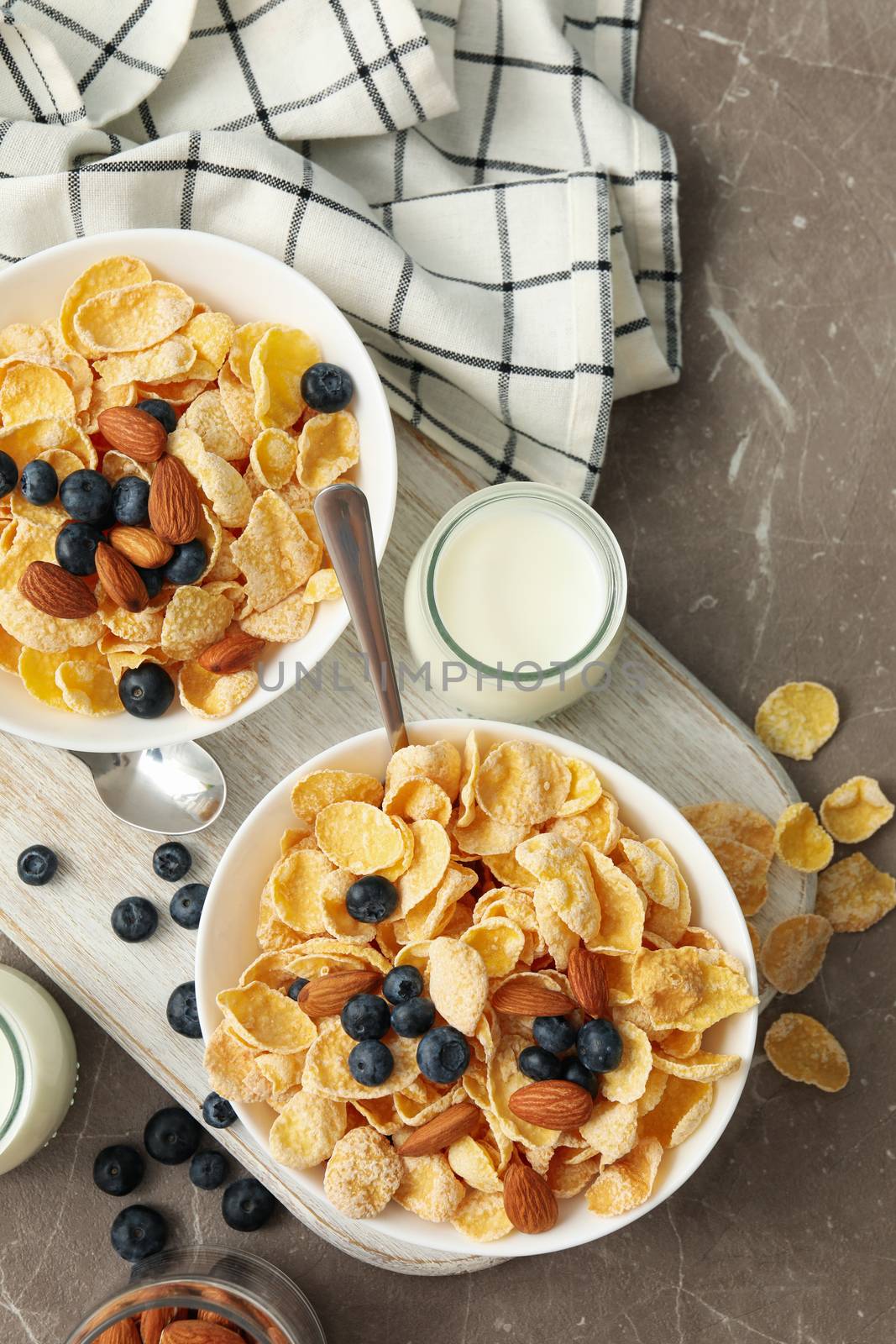 Concept of breakfast with muesli, berry, nut and milk on gray table