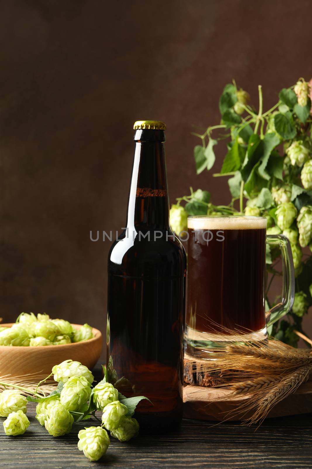 Beer, hop and wheat on wooden table against brown background by AtlasCompany