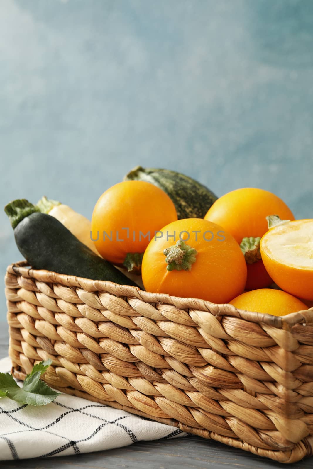 Basket with zucchini on napkin on wooden table by AtlasCompany