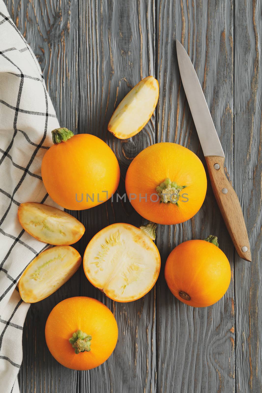 Round zucchini, knife and napkin on wooden background by AtlasCompany