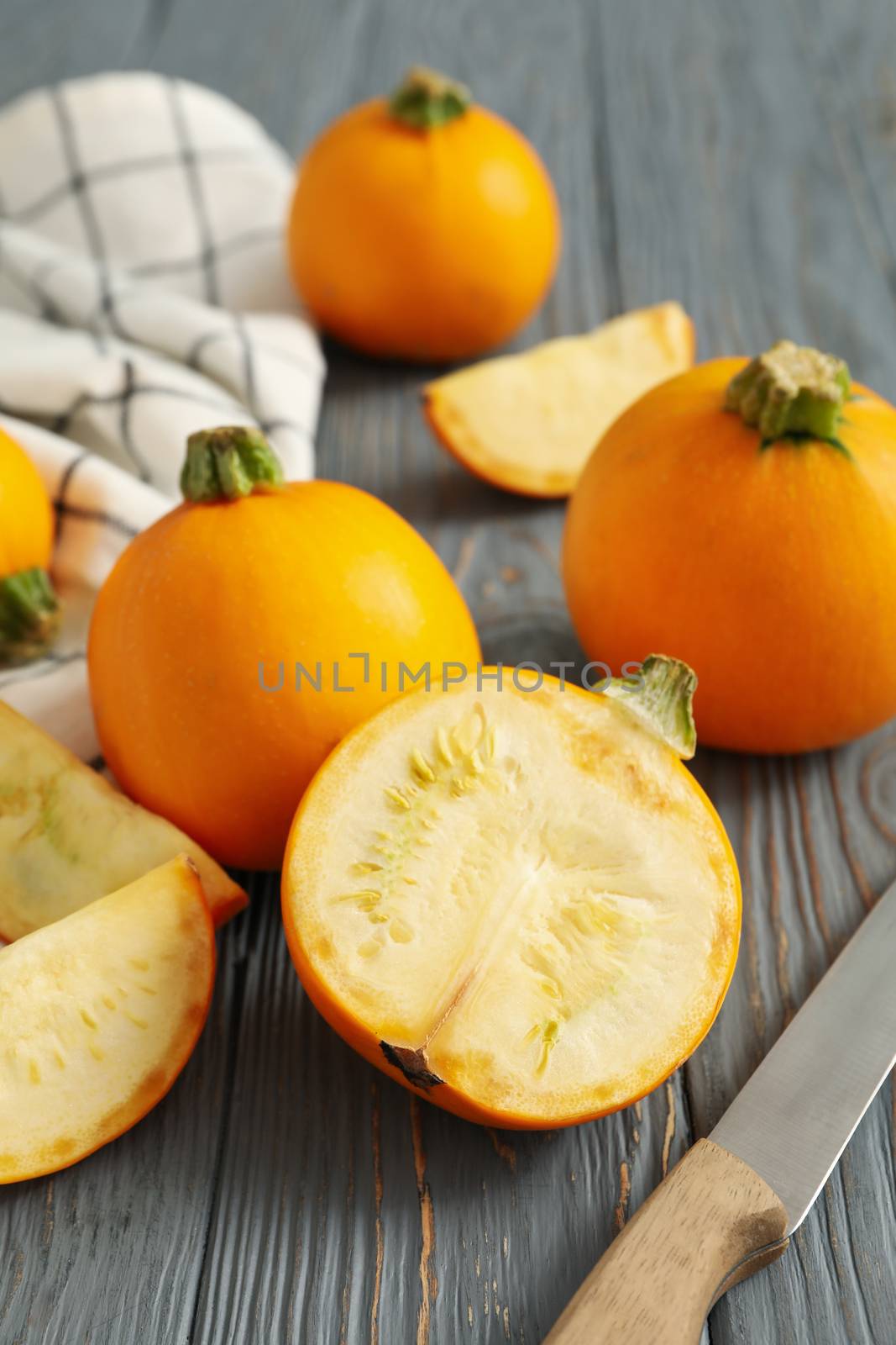 Round zucchini, knife and napkin on wooden background by AtlasCompany