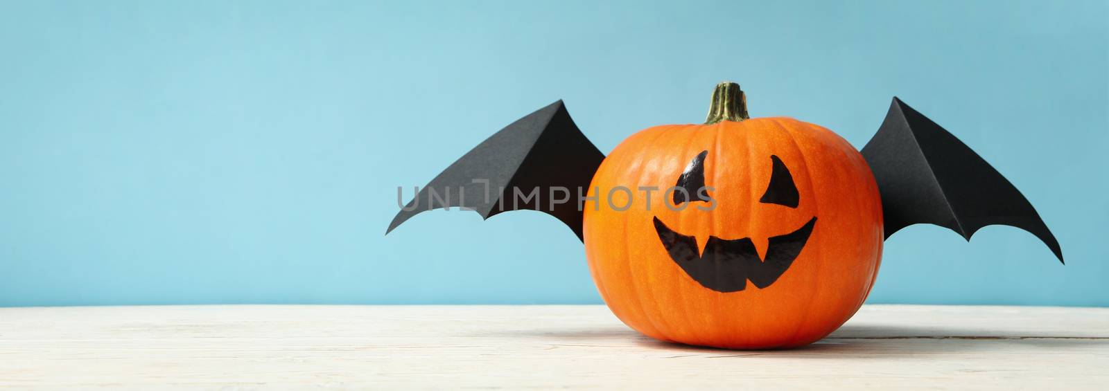 Pumpkin with smile and wings on blue background