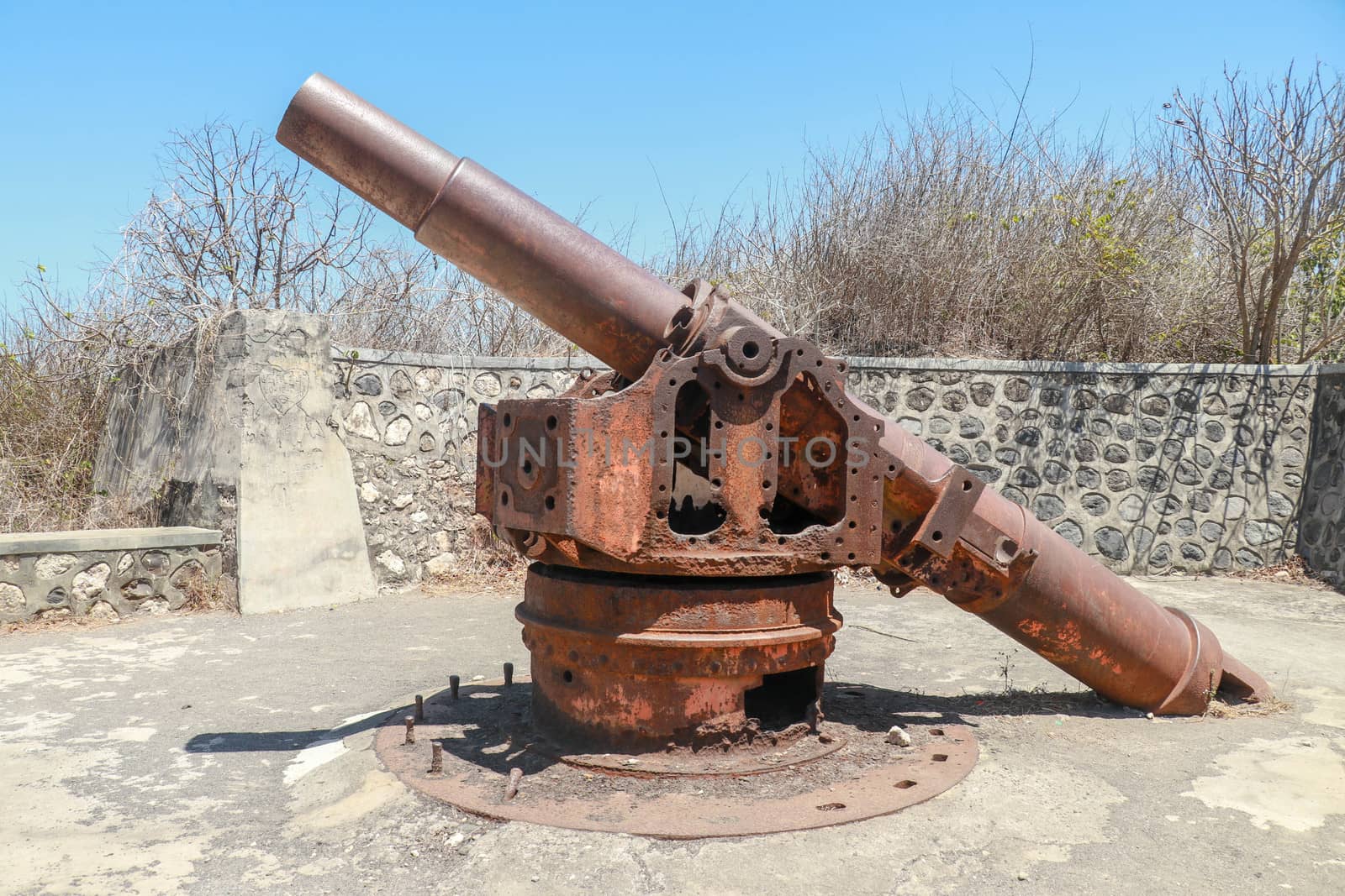 Old rusted cannon from World War II. Japanese cannon Meriam Jepang in a stone fortification on the island of Lombok in Indonesia. Color image of an old cannon on a sunny day.
