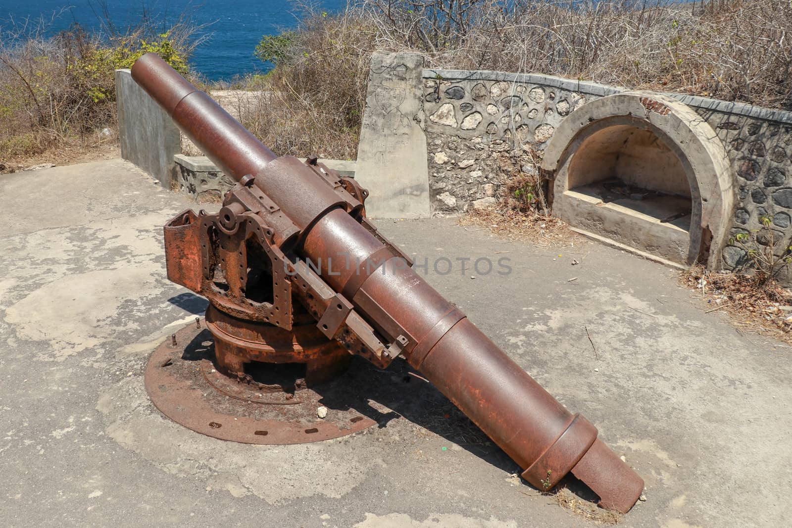 Back view from ancient cannon heading to the sea. These type of cannon were used in order to protect them from invaders in south of Brazil. Concept of protection and power. Cannon on sea background.