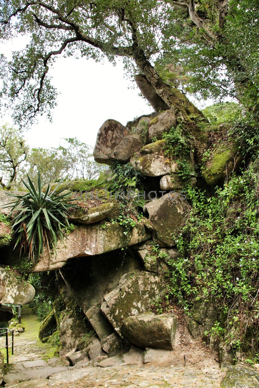 Stone arch with rocks in a Leafy garden with large trees in Sintra, Lisbon