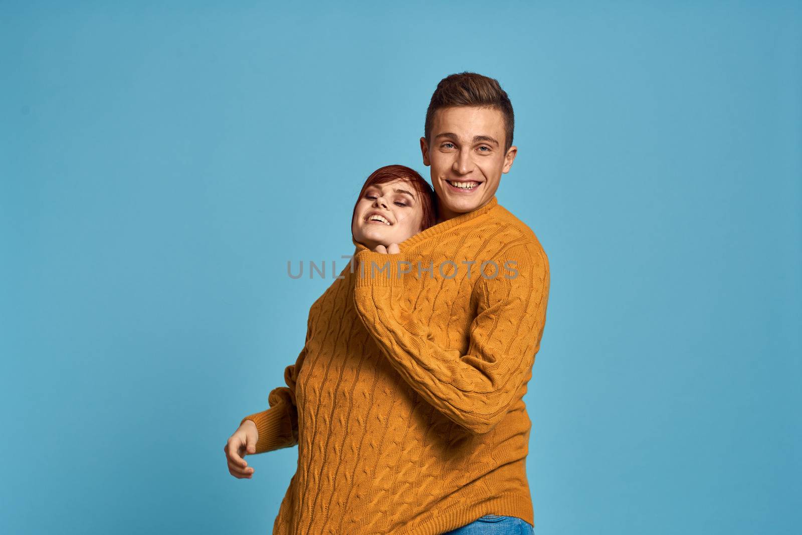 couple in yellow sweater posing against blue background cropped view. High quality photo