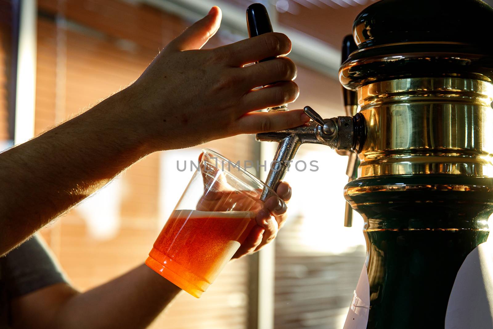 Pouring beer into a plastic glass. Sunset. by 9parusnikov