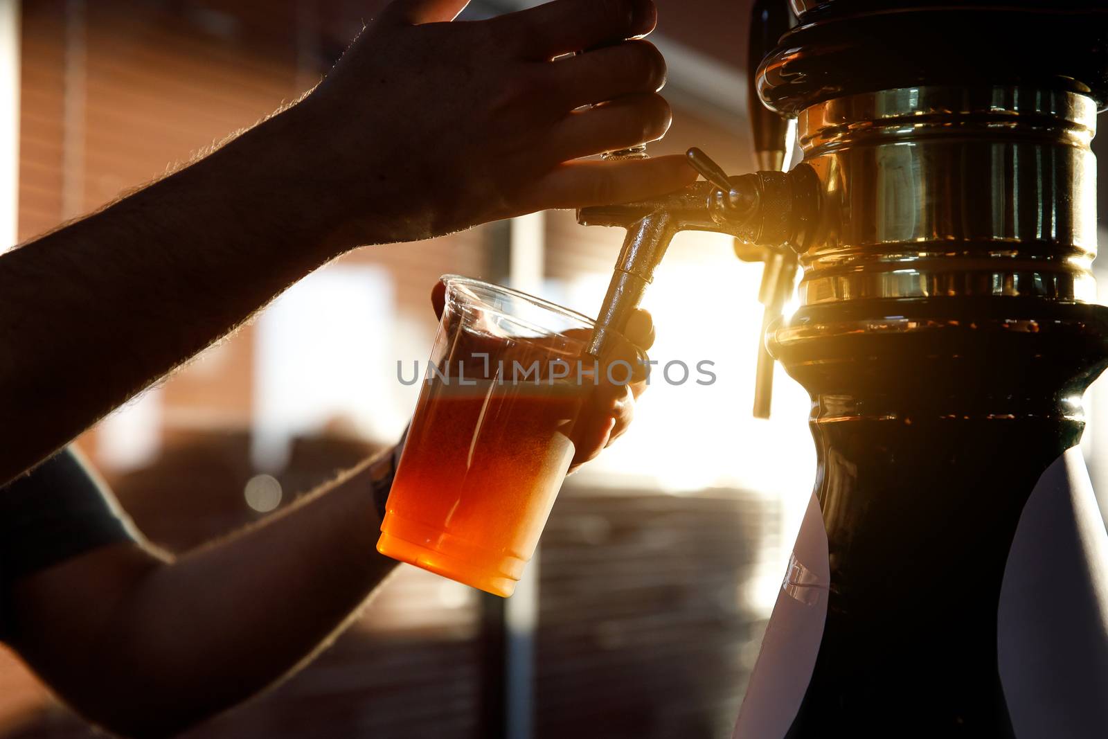 Pouring beer into a plastic glass. Sunset