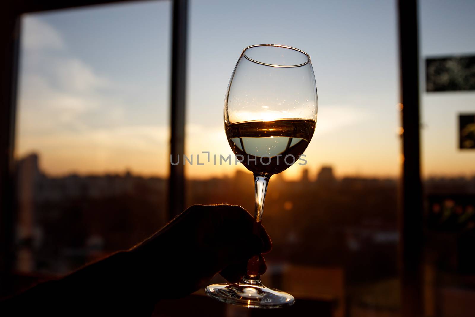 Wineglass over sunset. Window and city on the background