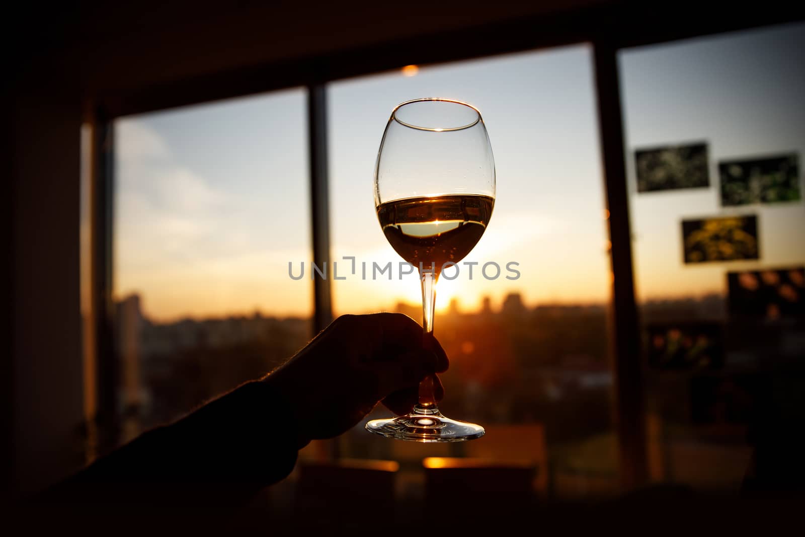 Wine glass in a hand over sunset. by 9parusnikov