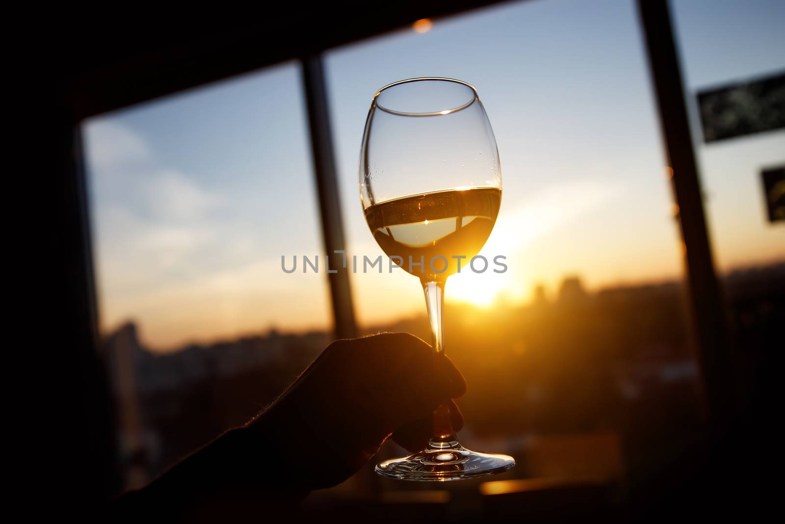 Wineglass over sunset. Window and city on the background