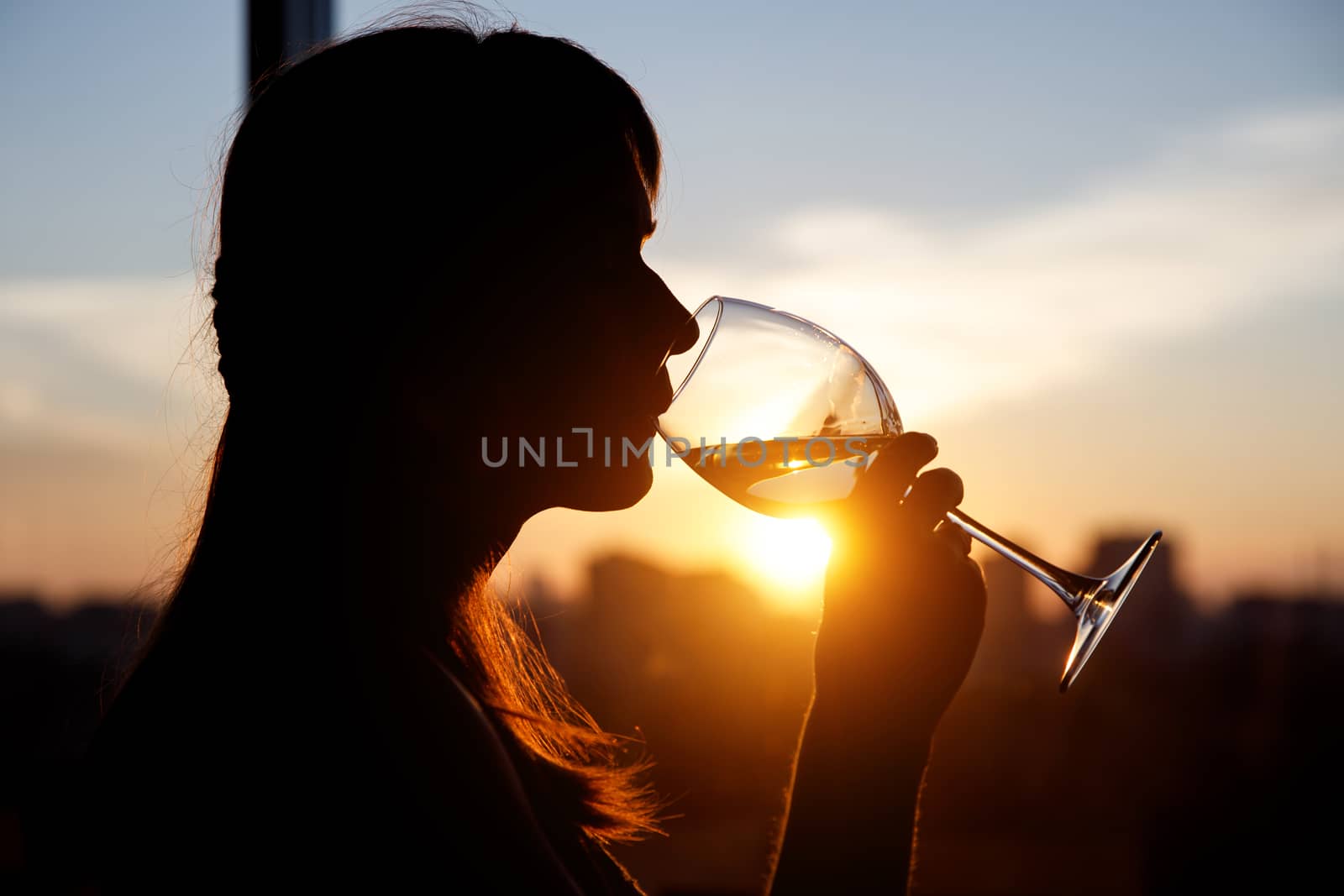 Girl drinking from a glass at sunset. by 9parusnikov