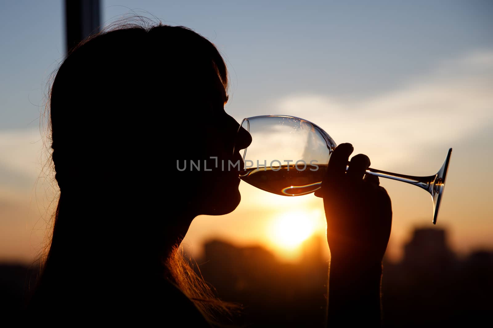 Girl drinking from a glass at sunset. by 9parusnikov