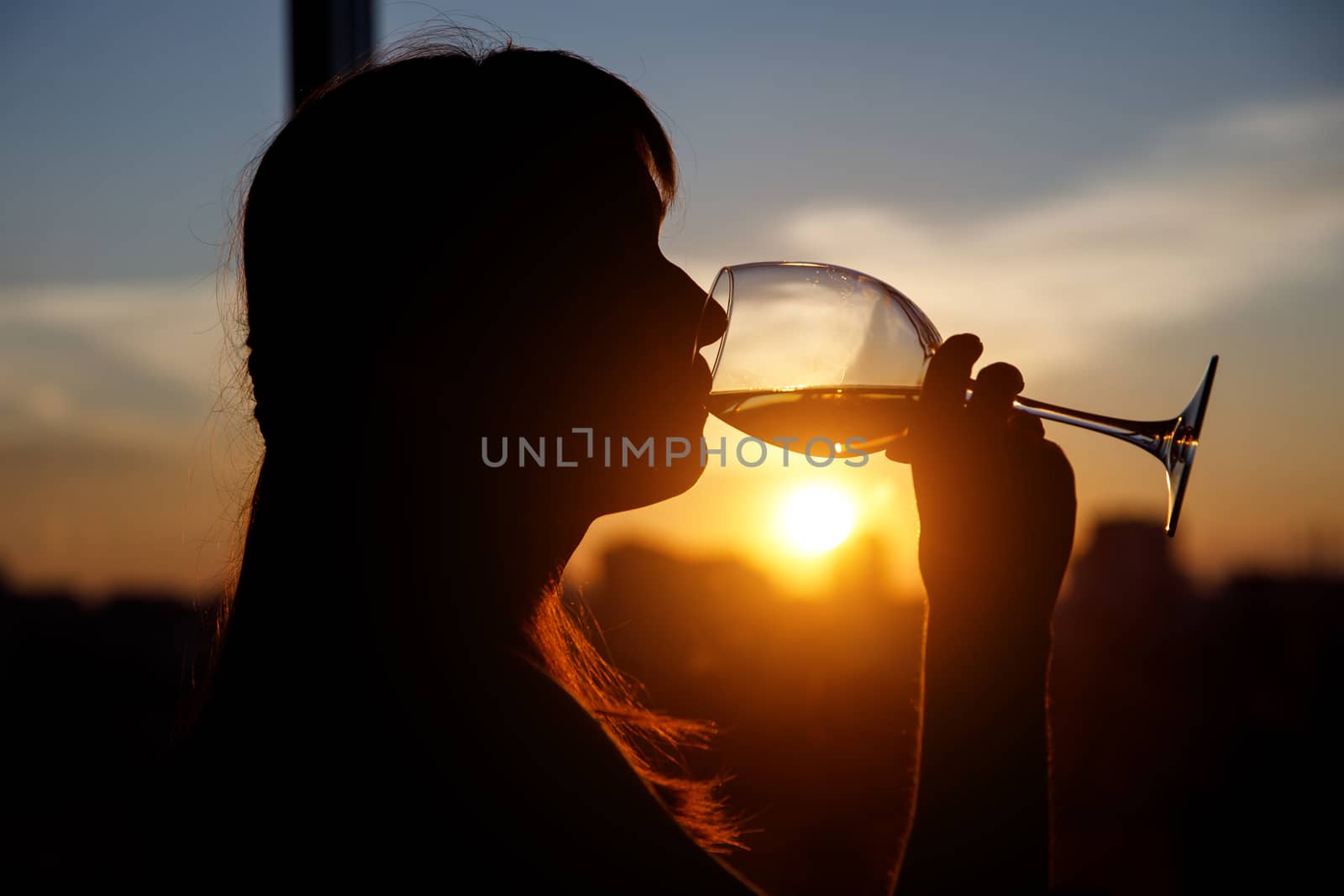 Girl drinking from a glass at sunset. by 9parusnikov