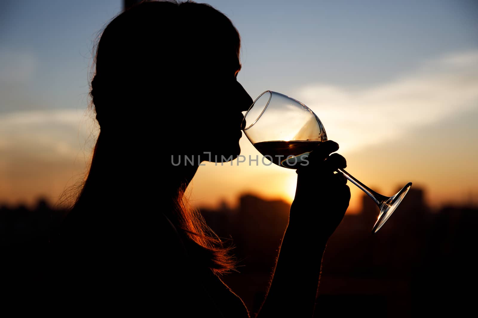 Girl drinking from a glass at sunset. by 9parusnikov