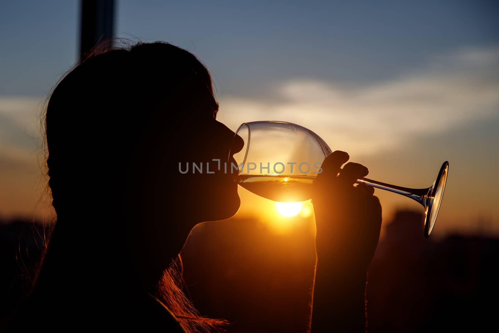 Girl drinking from a glass at sunset. by 9parusnikov