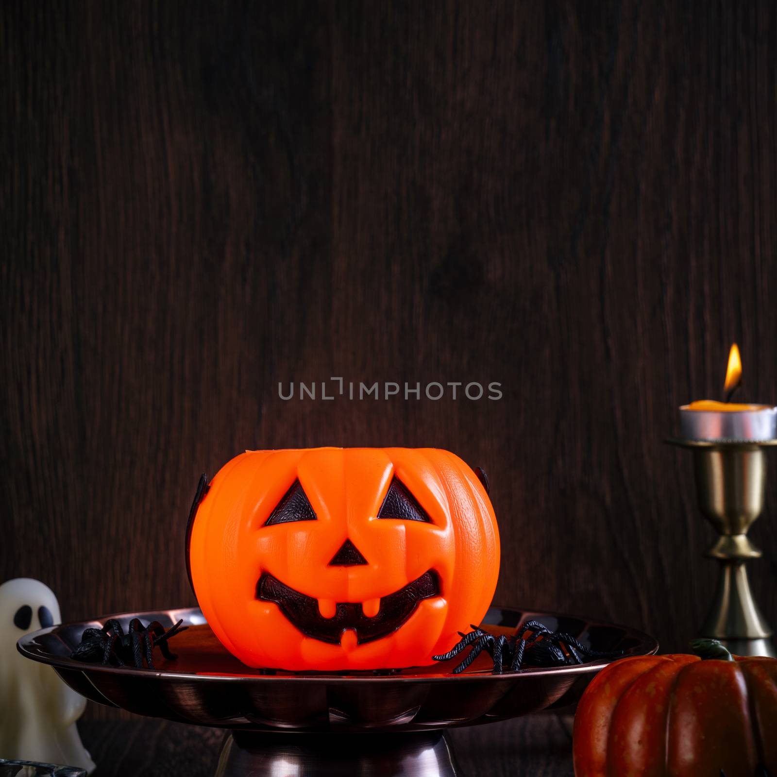 Close up of spooky Halloween tricks, concept of horror festival decor, pumpkin lantern with candlestick and smoke.