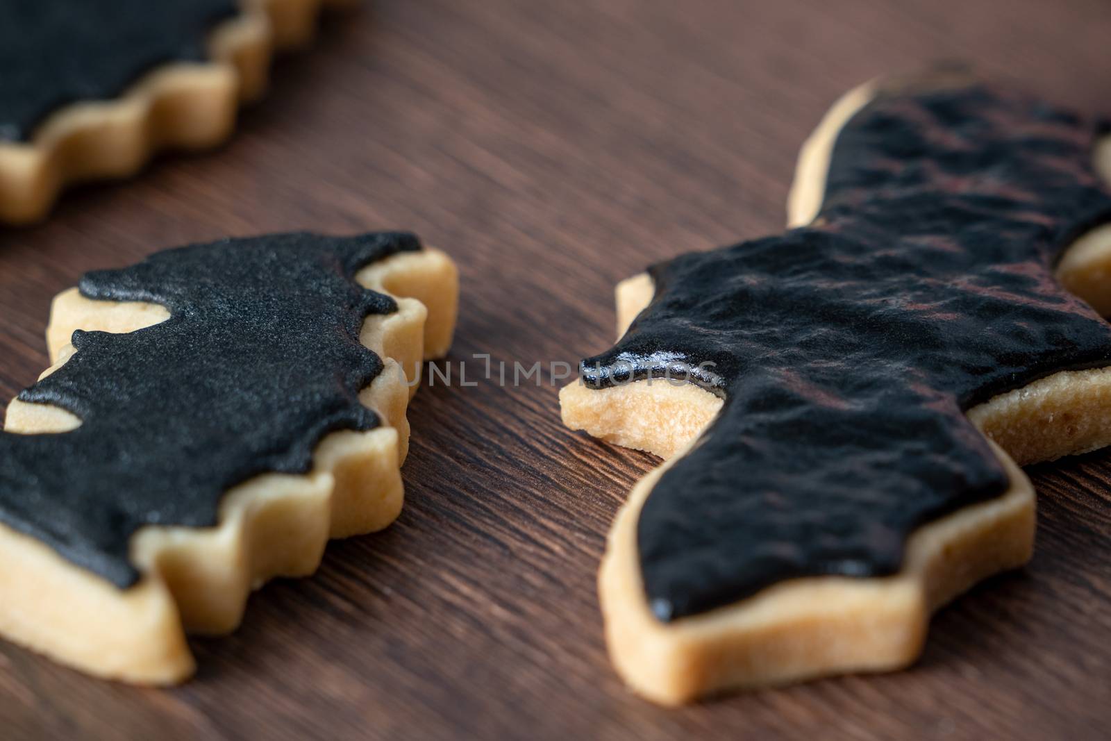 Close up of decorating cute Halloween bat gingerbread cookies with frosting icing cream topping bag.