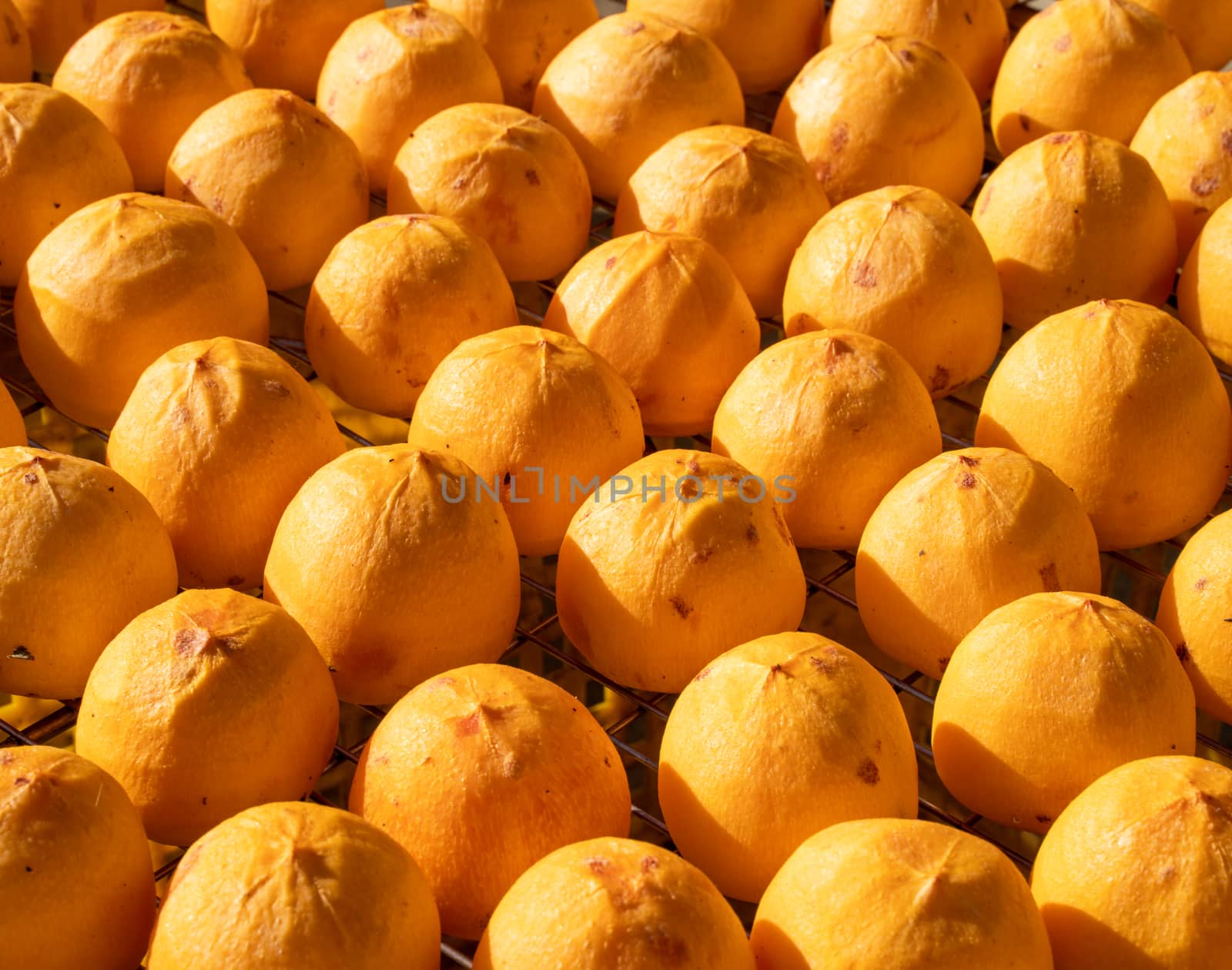 Making process of sun exposuring drying peeled dried persimmon in a sieve, autumn preserved food concept.