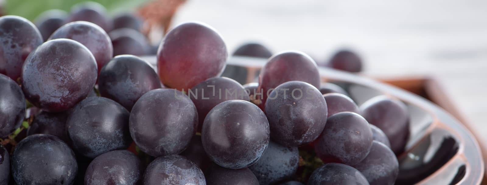 Close up of bunch of grapes fruit over wooden table background. by ROMIXIMAGE