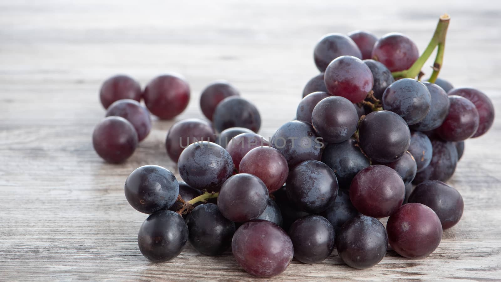 Delicious bunch of grapes fruit on a plate over wooden table background, close up.