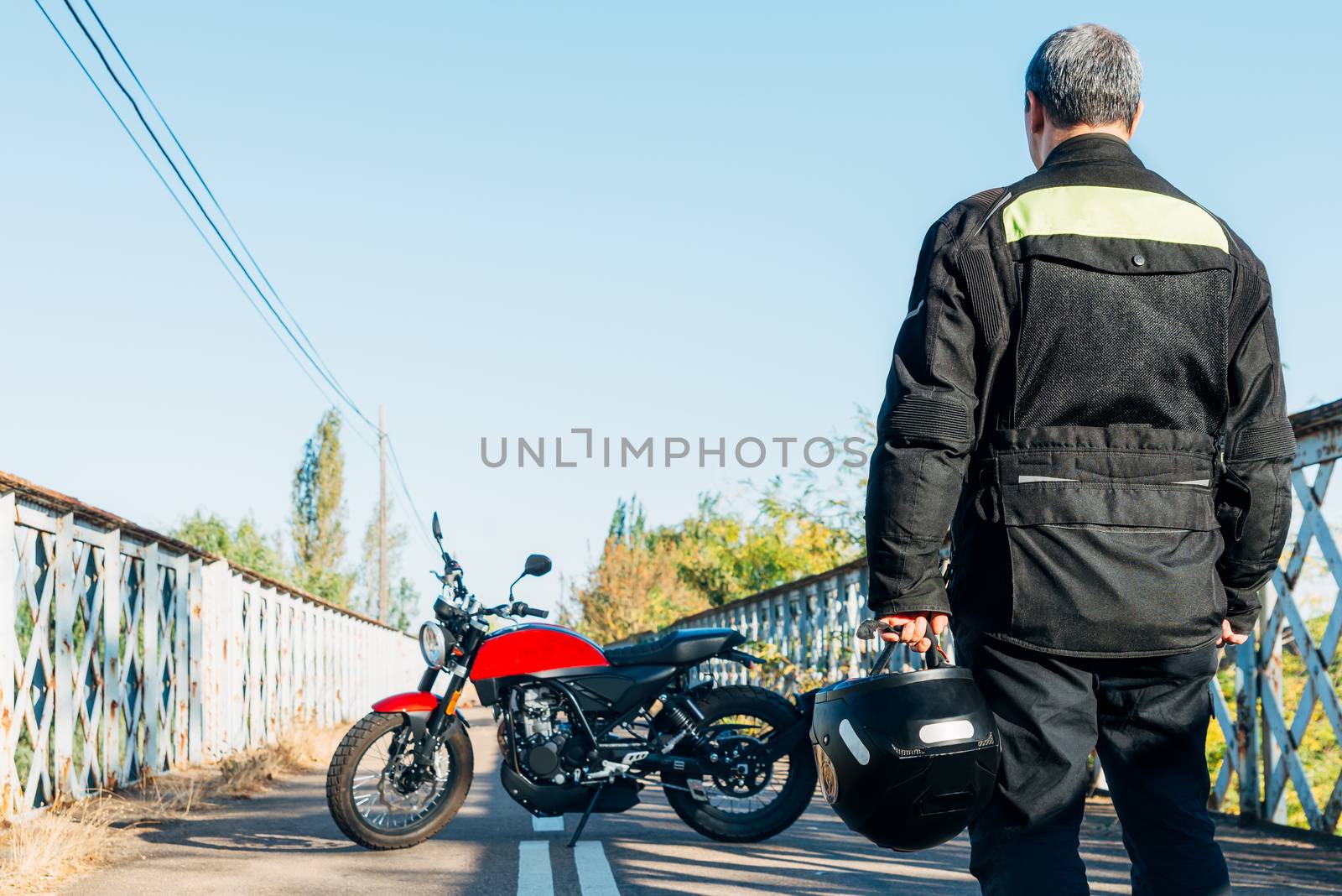 man on his back looking at a motorcycle with a helmet in his hand by Fotoeventis