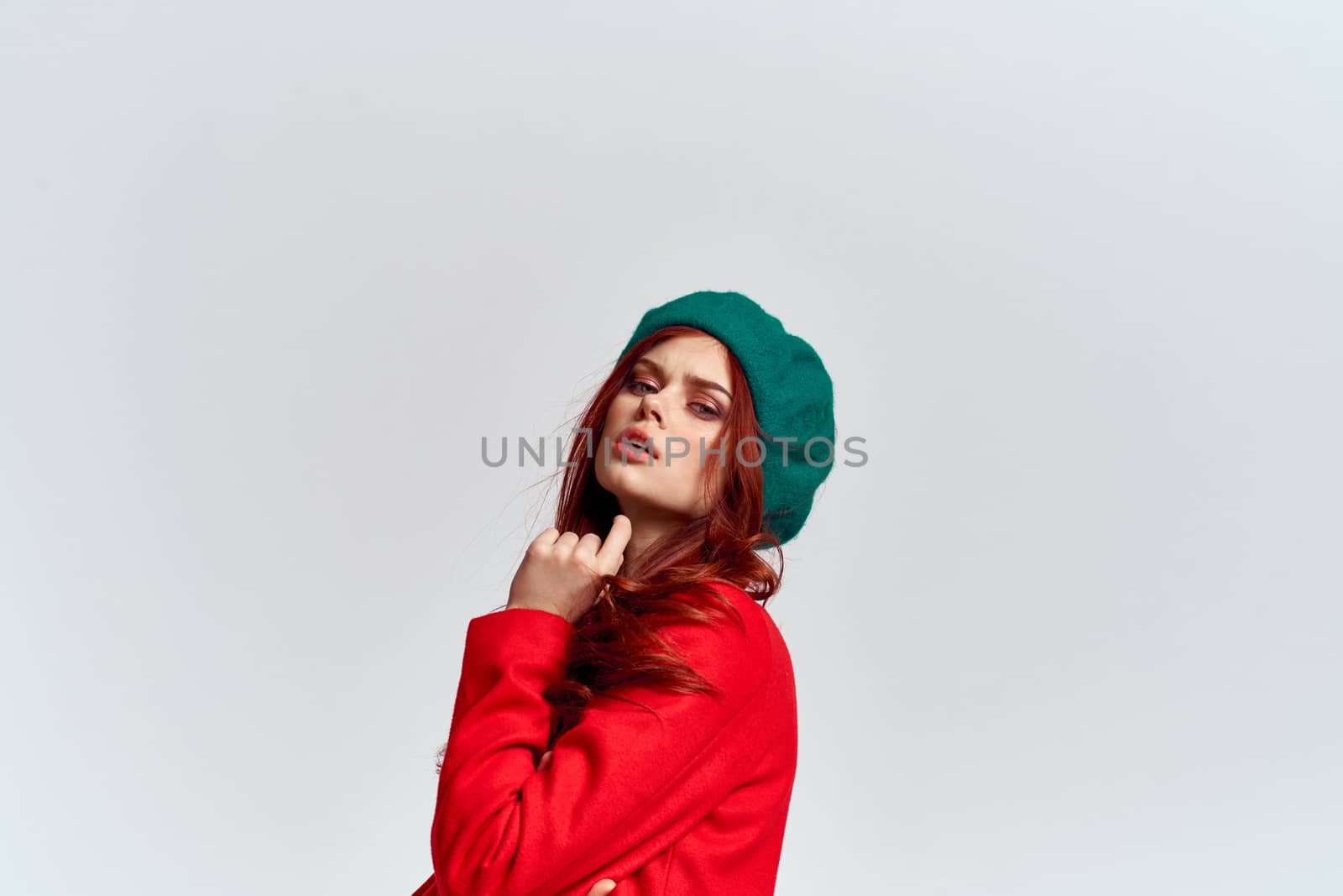 Woman in red coat and in green hat on isolated background cropped model with Copy Space emotions. High quality photo